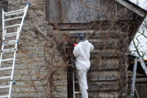 a Baldwin Restoration technician repairs a log cabin's exterior